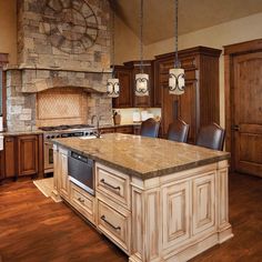 a large kitchen with an island in the middle and wood cabinets on both sides, along with a stone fireplace