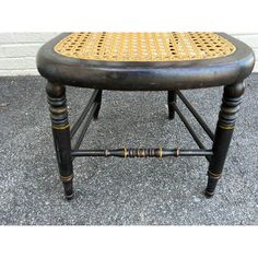 an old wooden stool with wicker seat and caned backrests on concrete ground