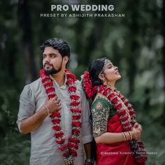 a man and woman standing next to each other with garlands around their necks in front of trees