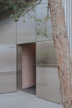 an open door in the side of a building next to a tree