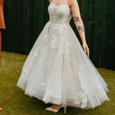 a woman in a white dress standing next to a fence