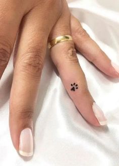 a woman's hand with a small dog paw tattoo on her left thumb and finger