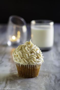 a cupcake sitting on top of a wooden table next to a glass of milk