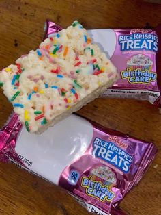 two bags of rice krispy treats sitting on top of a wooden table next to each other