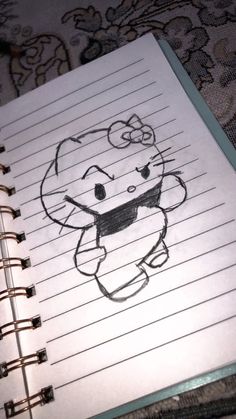 an open notebook with a drawing of a cat on top of it, sitting on a bed