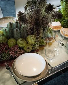 the table is set with plates, silverware and succulents