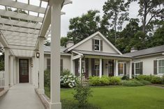 a white house with a pergolated walkway leading to the front door and porch