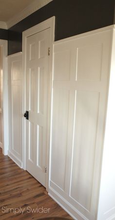 three white doors in a room with hard wood flooring and walls painted dark gray