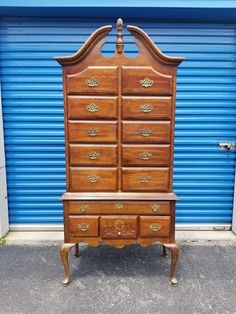 an old wooden dresser sitting in front of a blue garage door