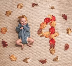 a baby is laying on the floor in front of fall leaves and an abc letter