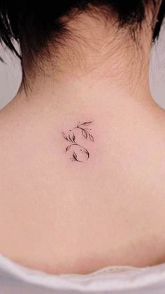 the back of a woman's neck with a small tattoo on her left side