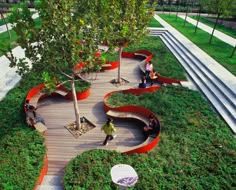 people are sitting on benches in the grass near trees and stairs that have been designed to look like waves