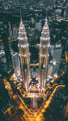 an aerial view of a city at night with tall buildings and street lights in the foreground