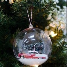 a christmas ornament with a red truck in the snow on top of a tree