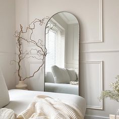 a white bedroom with a large mirror on the wall and a couch in the background