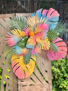 a wooden chair decorated with colorful paper flowers and palm leaf decorations on the back of it