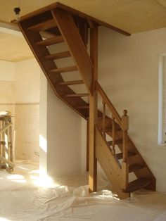 a wooden stair case in the corner of a room with white sheets on the floor