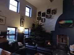 a living room filled with furniture and a fire place next to a wall mounted christmas tree