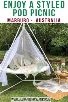 a teepee is set up in the grass with pillows on it and a table next to it