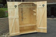 an open wooden cabinet sitting in the middle of a driveway next to a brick building