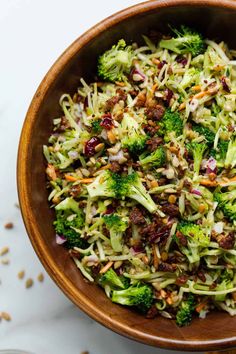 a wooden bowl filled with broccoli slaw and chopped nuts on the side