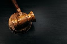 a wooden judge's gaven on top of a black table with a dark background