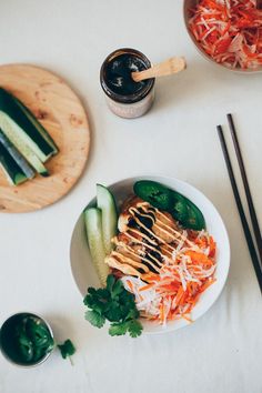 a white plate topped with meat and veggies next to chopsticks