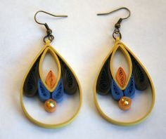 two pairs of earrings with blue, orange and black designs hanging from hooks on a white surface