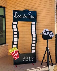 a movie themed display in front of a building with a popcorn bucket and film camera