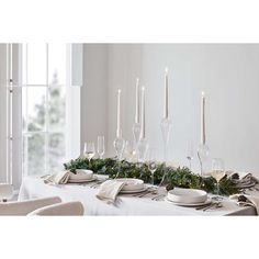 a table set with candles, plates and napkins