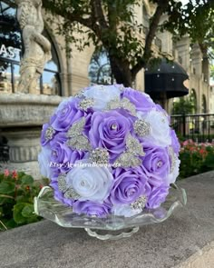 a bouquet of purple and white roses in a glass bowl