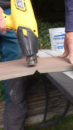 a person using a power drill to attach a piece of wood on top of a table