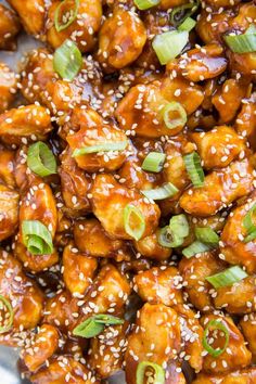 sesame seed chicken is served in a bowl with sesame seeds and green onions on top