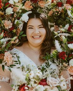 a woman with flowers in her hair is smiling at the camera while holding a bouquet