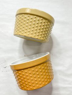 two yellow and white dishes sitting on top of each other