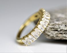 a yellow gold ring with baguetts of diamonds sitting on top of a rock