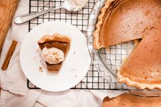 a slice of pumpkin pie on a plate next to a pie pan with a piece missing