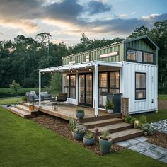 a house made out of shipping containers on top of a grass covered field with stairs leading up to it