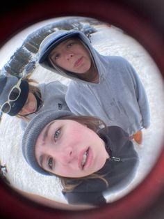 three people are looking at the camera through a circular lens, with snow in the background