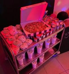 a pizza and cupcakes are on display in front of a pink light at a party