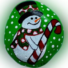 a painted rock with a snowman holding a candy cane