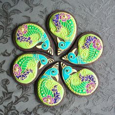 four decorated cookies sitting on top of a gray tablecloth covered in paisley patterns and swirls