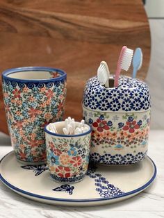 an assortment of toothbrushes and cups sitting on a plate next to each other