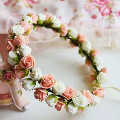 a pink and white flower crown on top of a table next to a pair of shoes