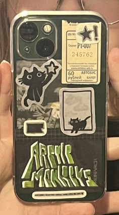 a person holding up a cell phone case with stickers on it