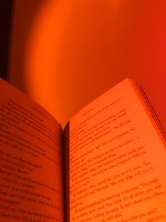 an open book sitting on top of a table next to a red light bulb in the background