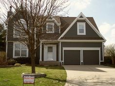 a house with a for sale sign in front of it and a tree on the lawn