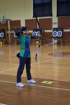 a woman is practicing archery in an indoor gym