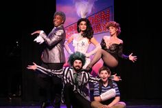 a group of people standing on top of a stage with clowns in the background