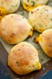 several rolls with cheese and herbs sitting on a baking sheet